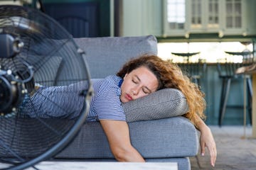 young woman sleeping in front of electric fan